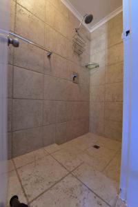 a bathroom with a shower with a tile floor at Kalbarri Sunset Villa in Kalbarri