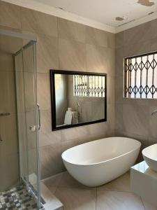 a bathroom with a large white tub and a sink at Swakhanya Haus in Vereeniging