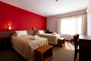 ein Hotelzimmer mit zwei Betten und einer roten Wand in der Unterkunft Pudu Lodge in El Chalten