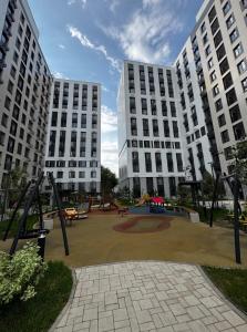 two large white buildings with a playground in a park at ЖК Tandau 399 in Almaty