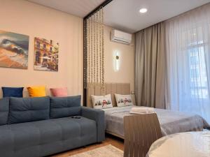 a living room with a couch and a bed at ЖК Tandau 399 in Almaty