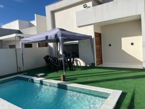 a house with a swimming pool with an umbrella at CASA MARECHAL FRANCÊs in Marechal Deodoro