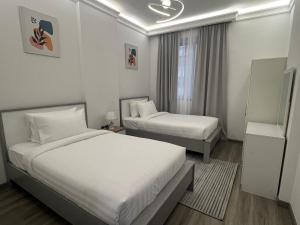a hotel room with two beds and a window at Nasma Homes Al Dana in Abu Dhabi