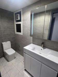 a bathroom with a sink and a toilet and a mirror at Nasma Homes Al Dana in Abu Dhabi
