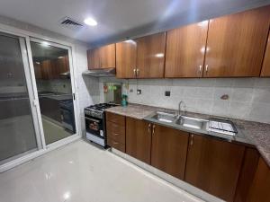 a kitchen with wooden cabinets and a sink at Nasma Homes Al Dana in Abu Dhabi