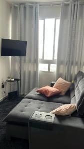 a living room with a couch and a large window at Doce lar in Pouso Alegre