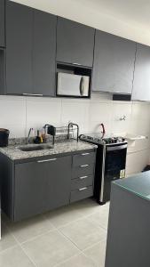 a kitchen with black and white cabinets and a microwave at Doce lar in Pouso Alegre +19 photos