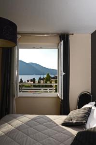 een slaapkamer met een raam met uitzicht op het water bij Hôtel La Réserve in Gérardmer