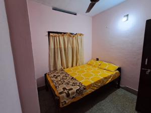 a small bedroom with a bed with a yellow blanket at A-Kutty in Irinjālakuda +5 photos