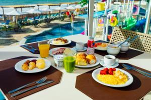 a breakfast table with plates of breakfast foods and drinks at Costeira Palace Beach Resort All Inclusive in Natal