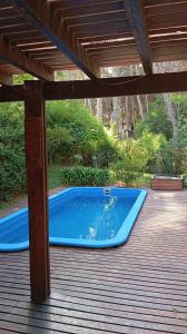 a blue swimming pool on a deck with a wooden roof at Casa con pileta, Mar Azul in Mar Azul