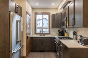 a kitchen with wooden cabinets and a sink and a window at Polar Peak Lodges by Fernie Central Reservations in Fernie