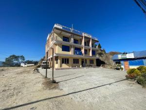 a large yellow building on a dirt road at Yolmo Hotel in Gorkhe