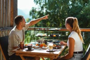 a man and a woman sitting at a table with food at Gailerhof Boutique Hotel B&B Dolomites in Monguelfo