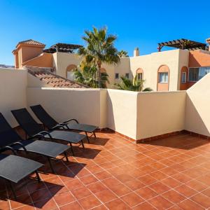 a group of chairs sitting on a patio with a building at Casa Ricardo Penthouse in Sitio de Calahonda