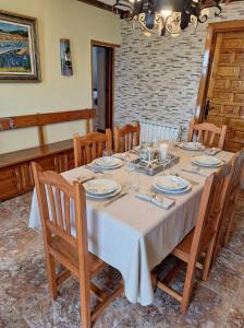 a dining room table with a white tablecloth and wooden chairs at El BurbyI in Somo