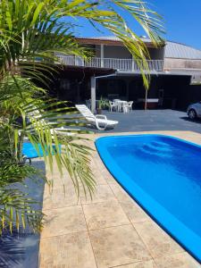 a pool with a palm tree and a house at Casa com piscina Ana Eliza in Cambé