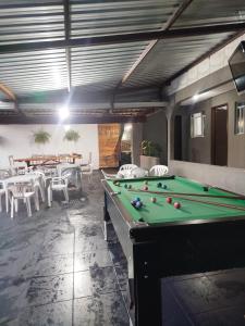 a room with a pool table and tables and chairs at Casa com piscina Ana Eliza in Cambé