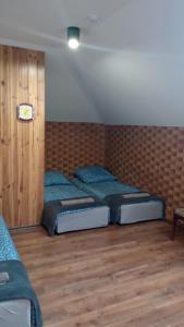 two beds in a room with wooden floors at Chmurka in Bęczków