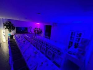 a room with a long table with chairs and purple lights at Domb Apartmanok in Sukoró