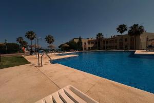 a large swimming pool with a bench in a resort at Casa Ricardo Penthouse in Sitio de Calahonda
