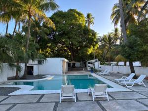 a swimming pool with chairs and palm trees at SunSal Garden Surf Hub in El Sunzal