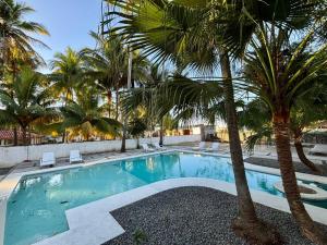 a swimming pool with palm trees in a resort at SunSal Garden Surf Hub in El Sunzal