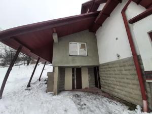 a house with a covered porch in the snow at Apartament 12 in Zwardoń
