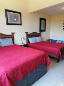two beds in a hotel room with red covers at Beautiful condo a few steps to sea in Cancún