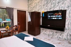 a bedroom with a bed and a tv on a wall at Corbett Nature Walk - Forest View Swimming Pool Retreat in Rāmnagar
