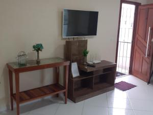 a living room with a flat screen tv and a table at COBERTURA Duplex com Visao do Mar, Village das ondas in Piúma