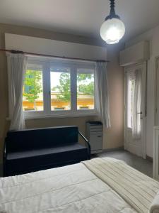 a bedroom with two beds and a couch and a window at EL RELOJ in Chascomús