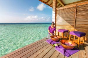 
a woman sitting on a bench in front of a body of water at Hurawalhi Island Resort in Kuredu
