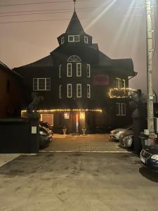 a large black building with cars parked in a parking lot at Broken bed hootel in Kaunas