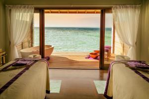 two beds in a room with a view of the ocean at Hurawalhi Island Resort in Kuredu