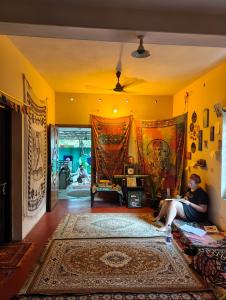 a woman sitting on a couch in a living room with a rug at JeeHaa Homestay in Alleppey