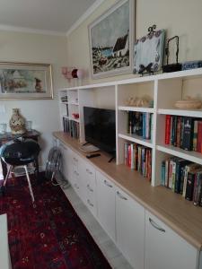 a room with a desk with a tv and books at The Treehouse! in Struisbaai