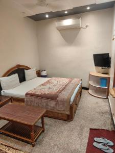 a bedroom with a bed and a table and a tv at Hotel Priyanka - 750 metres from nakki lake Near Bus Stand in Mount Ābu