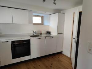 a kitchen with white cabinets and a sink at Apartment Günter by Interhome in Sagogn