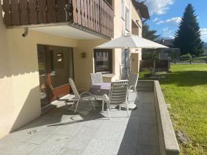 a patio with a table and chairs and an umbrella at Apartment Sassella 2a by Interhome in La Punt-Chamues-ch