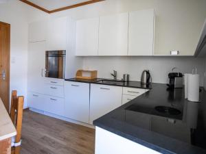 a kitchen with white cabinets and a black counter top at Apartment Chesa Müller by Interhome in Zuoz