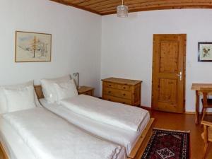a bedroom with two beds and a table and a wooden door at Apartment Chesa Müller by Interhome in Zuoz