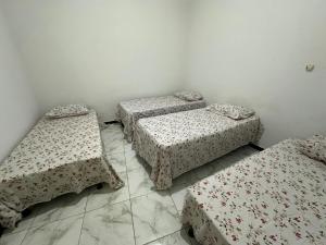 a room with three beds with covers on the floor at Casa aconchegante em Barra dos Coqueiros in Barra dos Coqueiros