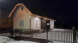 a house with a fence in the snow at night at Chata pod vŕškami Važca in Važec +21 photos