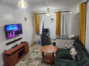 a living room with a green couch and a flat screen tv at Ansan Comfort in Gatunga