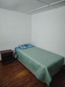 a bed in a white room with a nightstand and a bed sidx sidx sidx at Iquique Backpackers Beach House in Iquique