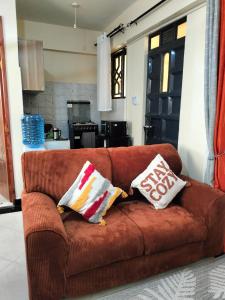 a brown couch with two pillows on top of it at Khalisee homes studio apartment 4 in Voi