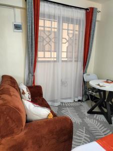 a living room with a brown couch and a window at Khalisee homes studio apartment 4 in Voi