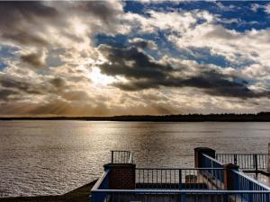 a view of the water from a dock with a cloudy sky at Apartment Heidestrauch by Interhome in Thülsfeld