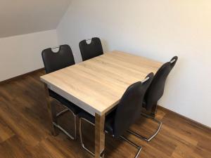 a wooden table with four black chairs around it at Apartment Heidestrauch by Interhome in Thülsfeld